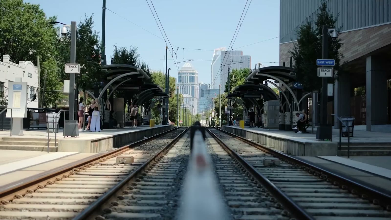 A symmetric view down light-rail tracks toward the Charlotte skyline
