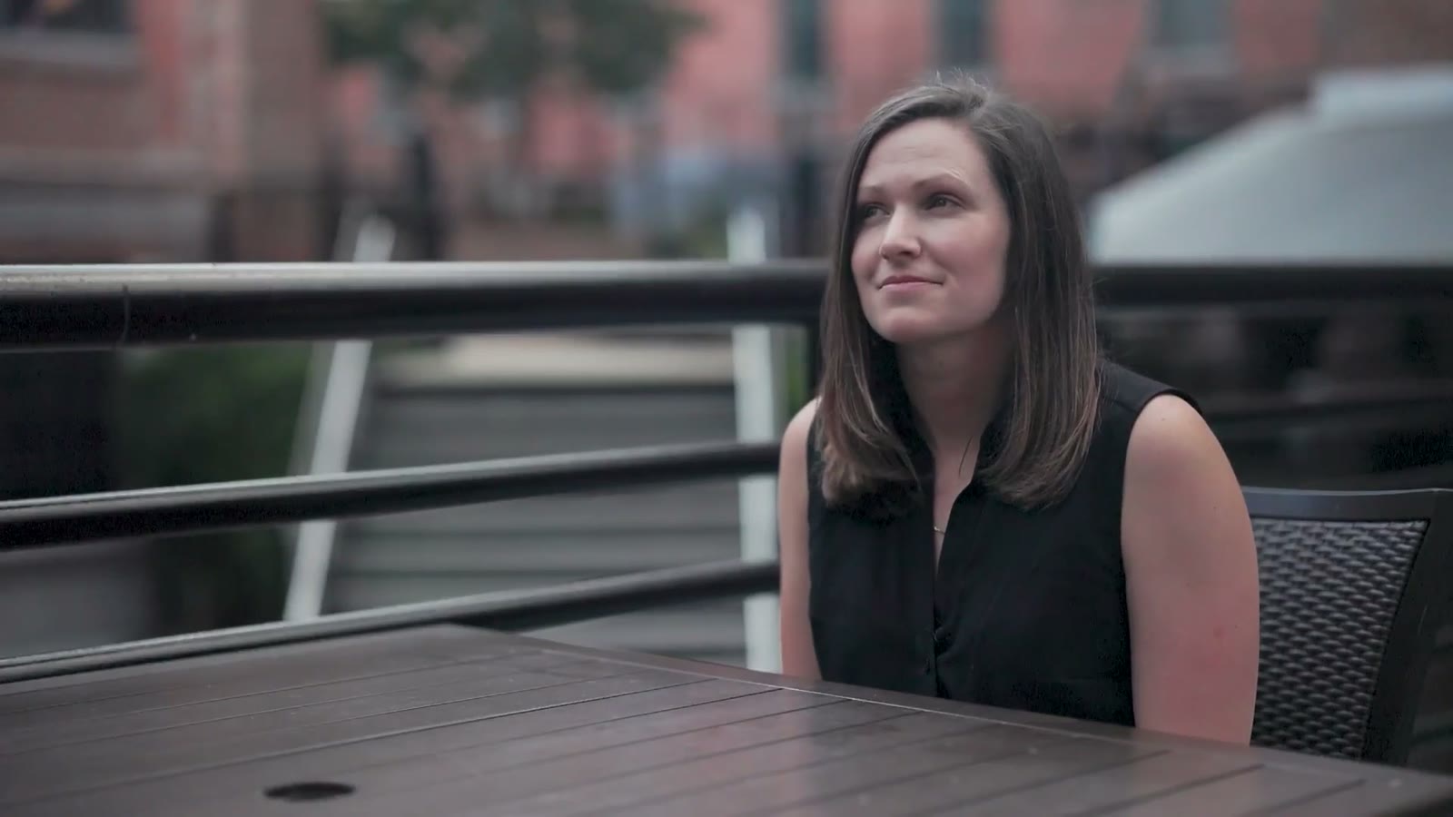 A woman at an outdoor cafe table lit by soft natural light